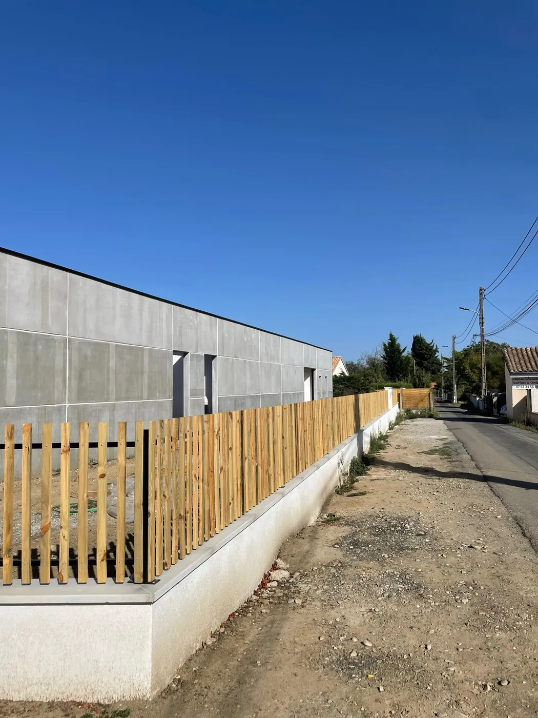 Clôture claustra en tasseaux de bois posée sur muret béton, réalisation ManufactureVB