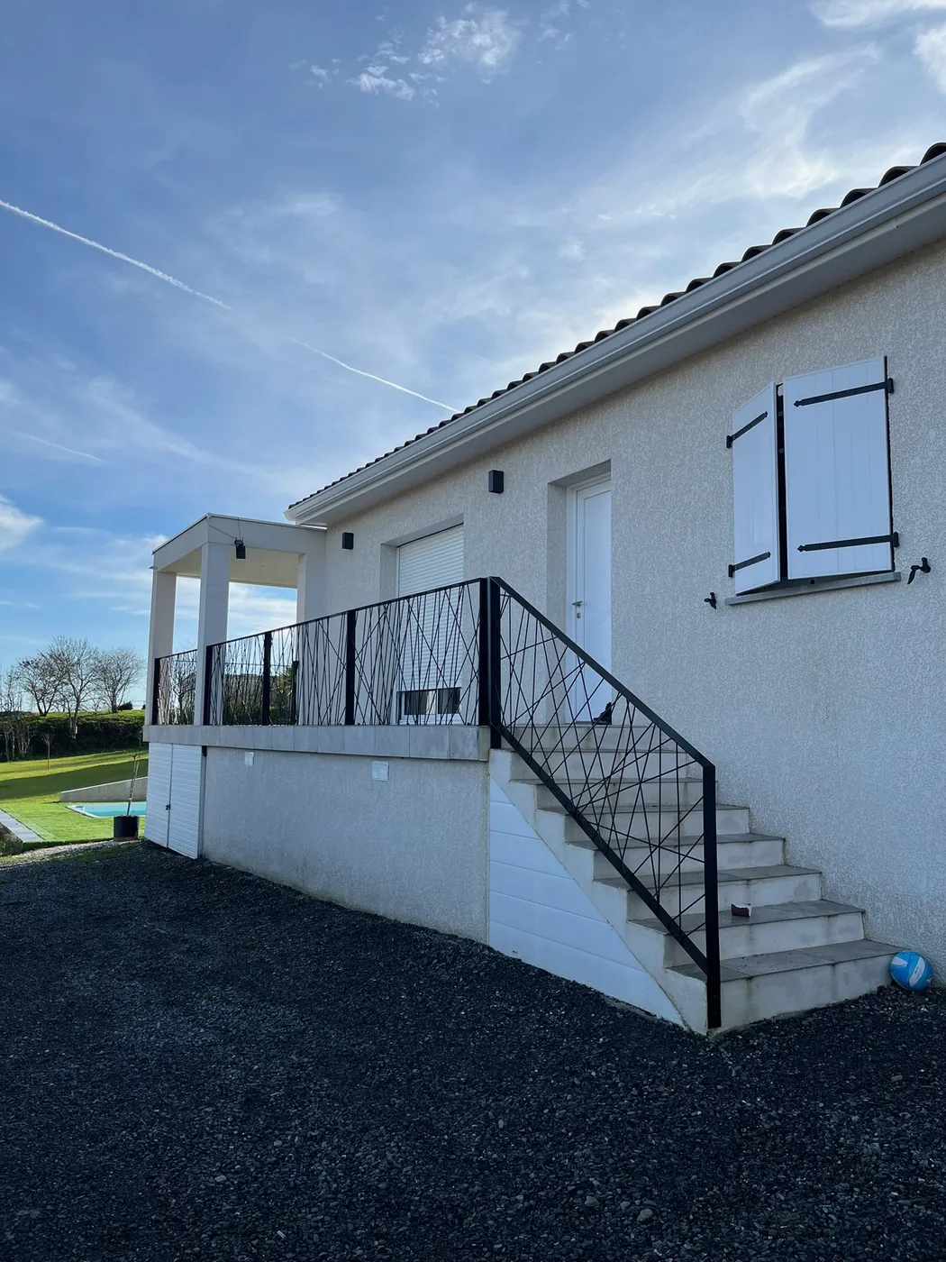 Garde-corps et rampe d'escalier extérieurs en métal noir à motifs croisés le long d'une terrasse de maison, réalisation ManufactureVB en Haute-Garonne