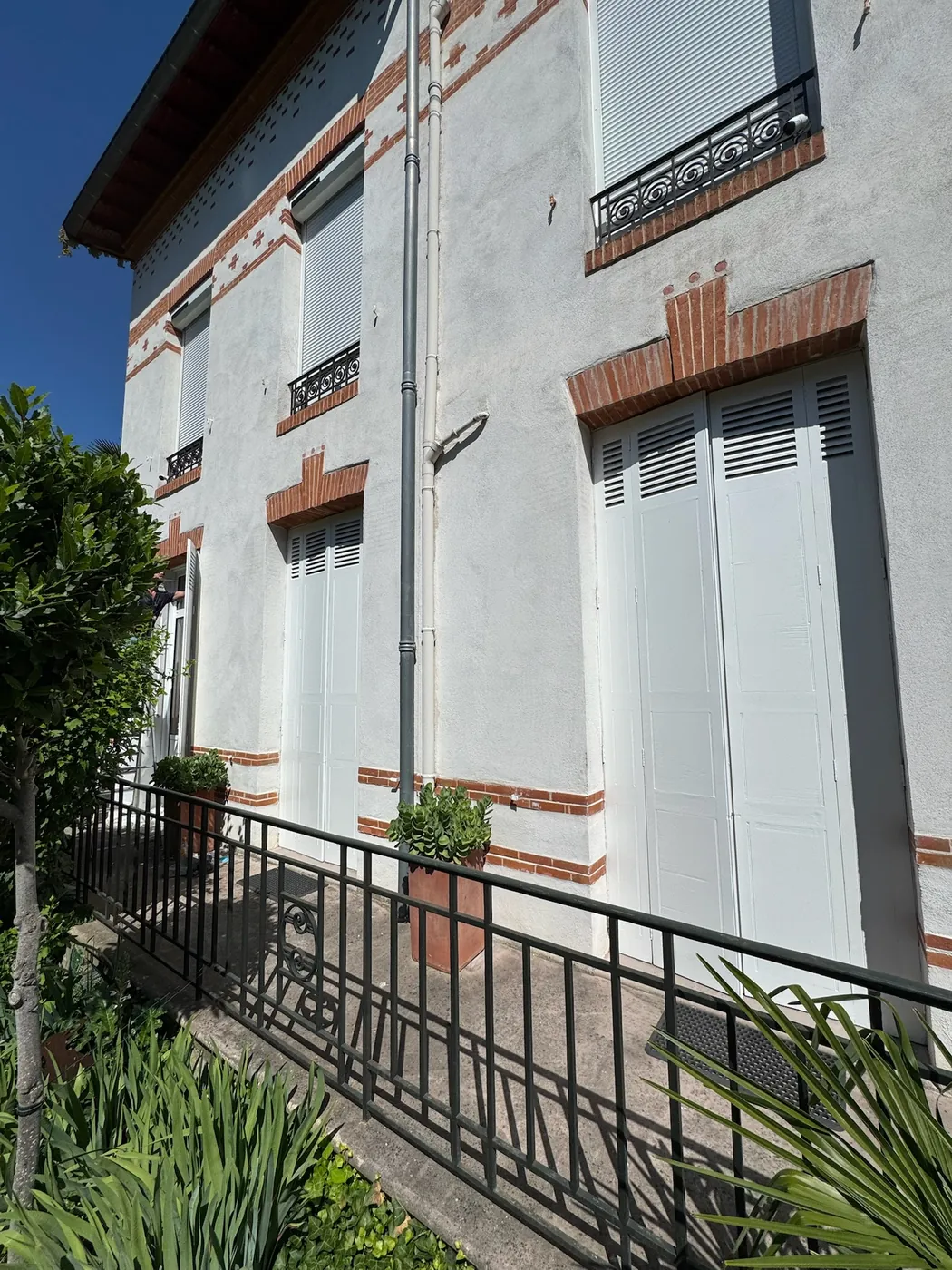 Rambarde en fer et volets bois remis en état sur la façade brique d'une maison toulousaine après sinistre