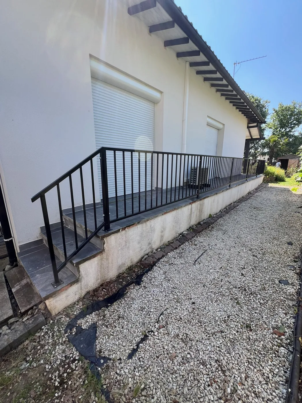 Garde-corps en acier thermolaqué noir à barreaudage vertical avec rampe d'escalier, posé sur une terrasse surélevée par ManufactureVB