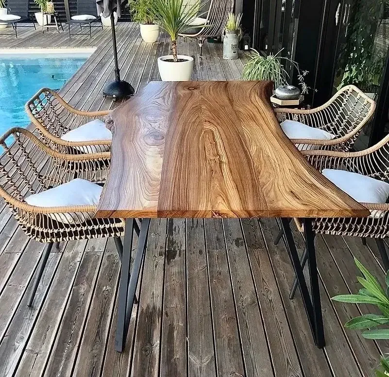 Table en noyer massif à bord naturel avec piètement métal, installée sur une terrasse en bois, création sur mesure ManufactureVB