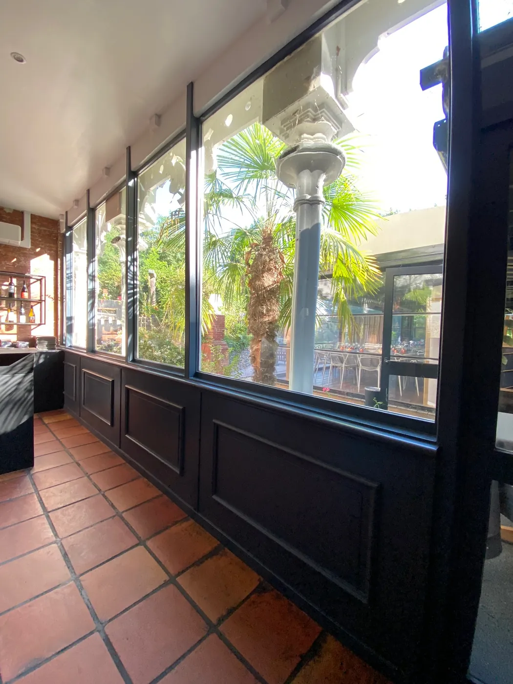 Verrière et menuiserie en métal noir avec soubassement bois dans la salle d'un restaurant à Toulouse, réalisation ManufactureVB